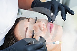 Doctor cosmetologist prepares the patient for the lip augmentation procedure with filler injection.