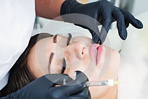Doctor cosmetologist prepares the patient for the lip augmentation procedure with filler injection. photo