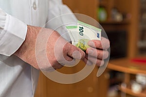 Doctor counting 100 Euro banknotes. Paid medical services healthcare concept