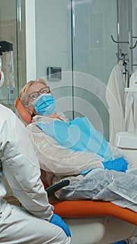 Doctor in coverall showing to patient x-ray on stomatological monitor