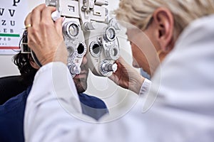 Doctor with customer in vision test or eye exam for eyesight by doctor, optometrist or ophthalmologist. Senior optician