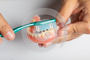 Carefully cleaning dental prosthesis with toothbrush photo