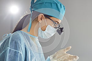 Doctor dentist with dental binocular loupes in blue medical uniform at work in dentistry clinic