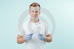 Doctor dentist holding dental instrumentation in his hands on light blue background. Smile healthy teeth concept