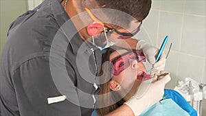 Doctor dentist treats a woman`s teeth from caries in an out-patient department