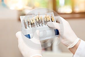 Doctor dentist woman holding tooth shade guide at clinic