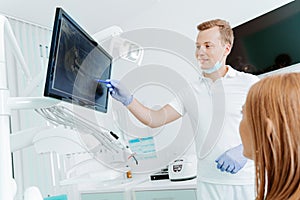 Doctor dentist and woman patient watching x-ray on digital screen in stomatology clinic with medical equipment. Smile healthy