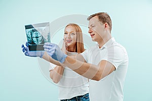 Doctor dentist and woman patient watching x-ray foto with teeth in in light blue background in dental clinic. Smile healthy teeth