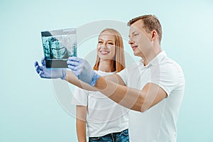 Doctor dentist and woman patient watching x-ray foto with teeth in in light blue background in dental clinic. Smile healthy teeth