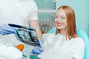 Doctor dentist and woman patient watching x-ray foto with teeth in stomatology clinic with medical equipment. Smile healthy teeth