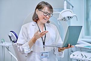 Doctor dentist working in office, using laptop, making video call conference