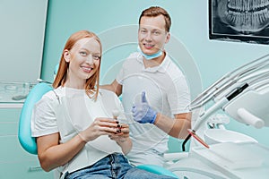 Doctor dentist and young woman patient smiling in dental clinic with medical equipment, x-ray dental, tools. Smile healthy teeth