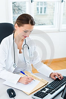 Doctor at desk in clinic writing a file or dossier