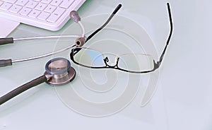 Doctor desk with glasses,keyboard,mouse pad and stethoscope with