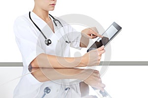 Doctor at desk touch tablet in medical office, remot control