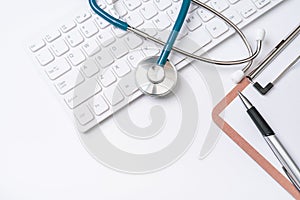 Doctor diagnoses concept - stethoscope on computer keyboard with medical record case and pen on white working table. Top view,