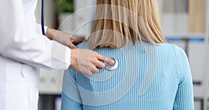 Doctor diagnoses patient breathing with stethoscope rear view