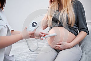 Doctor diagnosing pregnant woman and listening heart beat.