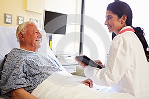 Doctor With Digital Tablet Talking To Patient In Hospital