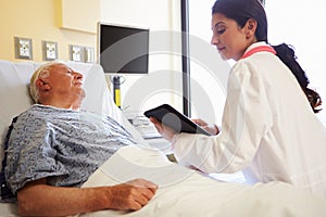 Doctor With Digital Tablet Talking To Patient In Hospital