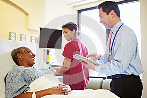 Doctor With Digital Tablet Talks To Woman In Hospital Bed