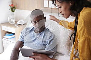 Doctor With Digital Tablet Visiting And Talking With Male Patient In Hospital Bed