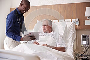 Doctor With Digital Tablet Visiting And Talking With Senior Male Patient In Hospital Bed