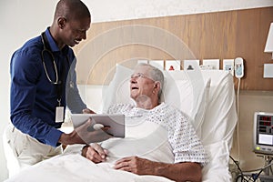Doctor With Digital Tablet Visiting And Talking With Senior Male Patient In Hospital Bed
