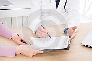 Doctor discusses with female patient medical contract at the clinic, medical insurance