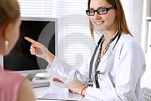 Doctor discussing confidental medical history with his patient and pointing at monitor computer