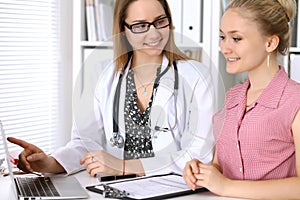 Doctor discussing confidental medical history with his patient and pointing at monitor computer