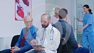Doctor discussing diagnosis with old man in hospital waiting area