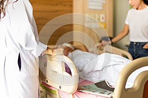 Doctor discussing with patient daughter while patient`s in bed at hospital.