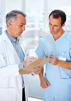 Doctor discussing prognosis with nurse. Doctor and nurse discussing patient chart.