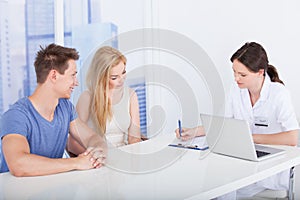 Doctor discussing report with young couple in clinic