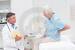 Doctor discussing reports with patient suffering from back pain