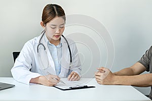 Doctor discussing to explaining disease and symptoms of patient during to writing diagnostic, prescription