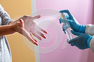 Doctor disinfecting patient`s hands with hand sanitizer