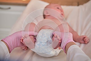 The doctor does gymnastics and massage to a newborn baby. Nurse in uniform doing warm-up exercises to the child