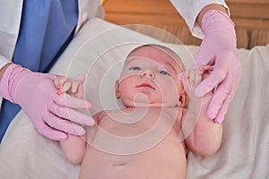 The doctor does gymnastics and massage to a newborn baby. Nurse in uniform doing warm-up exercises to the child