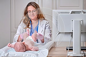 The doctor does gymnastics and massage to a newborn baby. Nurse in uniform doing warm-up exercises to the child