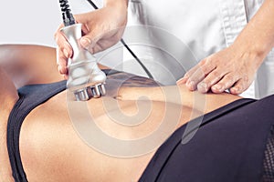 The doctor does the Rf lifting procedure on the stomach and hips of a woman in a beauty parlor.