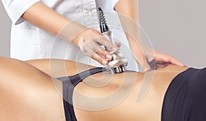 The doctor does the Rf lifting procedure on the stomach and hips of a woman in a beauty parlor.