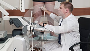 The doctor does ultrasound examination of the legs in the patient. A man with varicose veins came to the doctor for