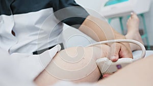 doctor does an ultrasound of the veins on the patient's legs. A phlebologist checks the veins on a woman's legs