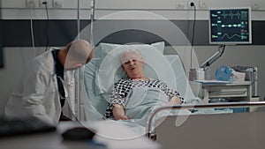 Doctor doing consultation with senior patient in hospital ward