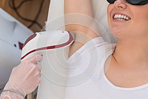 Doctor doing laser hair removal on a woman& x27;s armpit in the salon. An alternative way to permanently remove unwanted