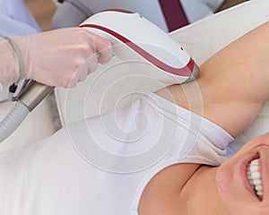 Doctor doing laser hair removal on a woman& x27;s armpit in the salon. An alternative way to permanently remove unwanted body