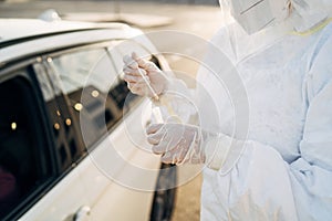 Doctor doing a PCR test COVID-19 on a patient through the car window.