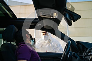 Doctor doing a PCR test COVID-19 on a patient through the car window.